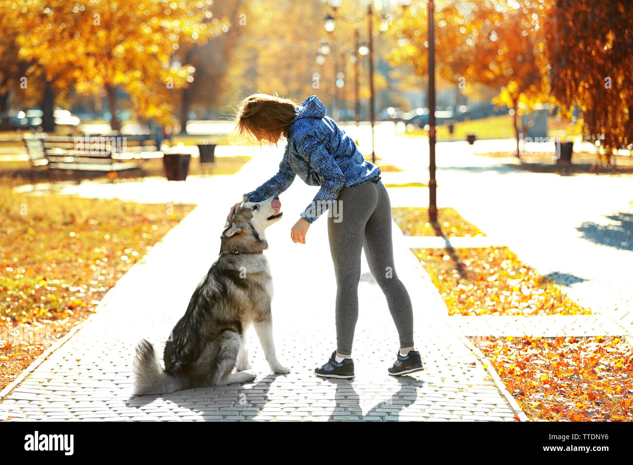 Happy young woman walking with her dog in park Stock Photo - Alamy