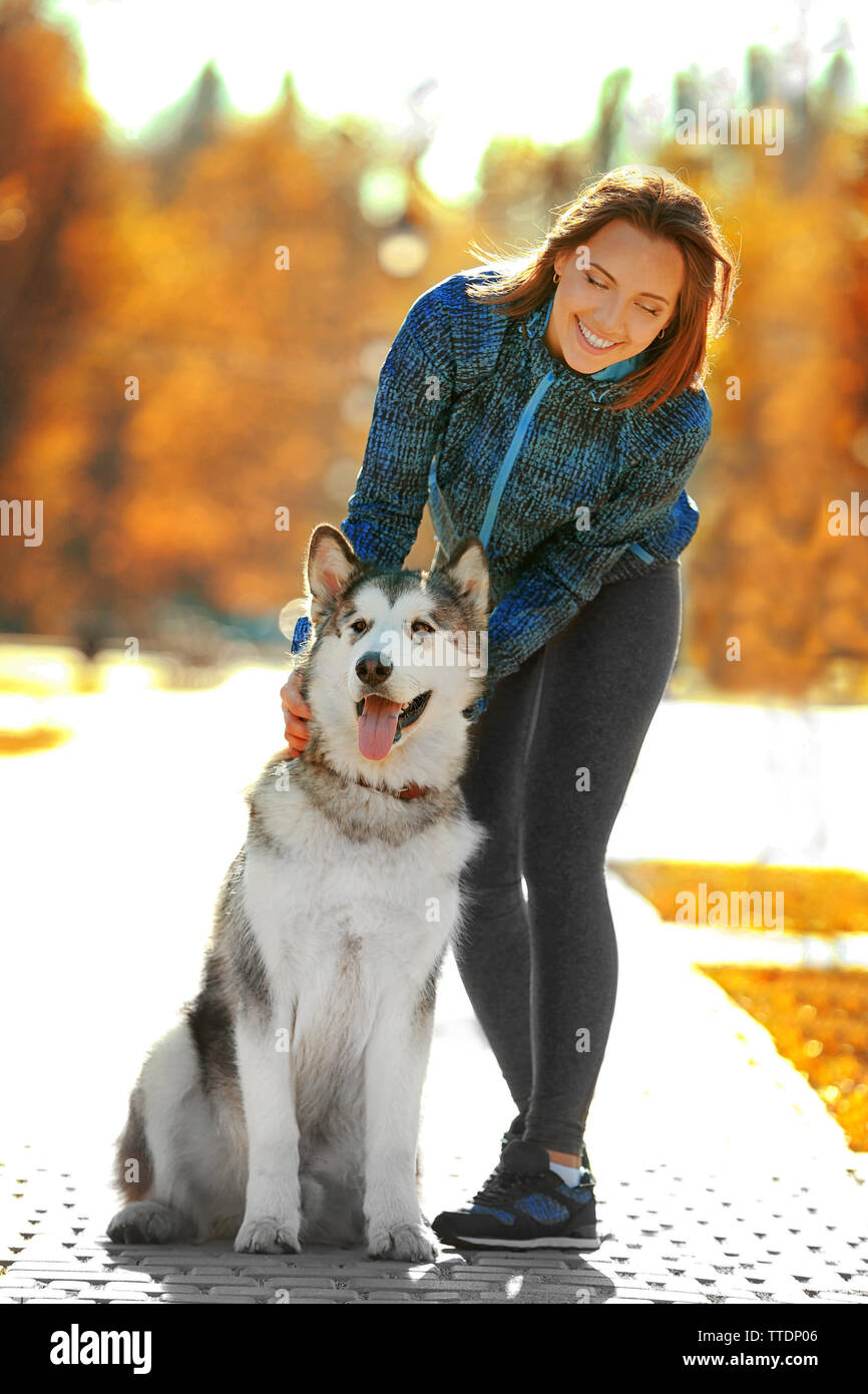 Happy young woman walking with her dog in park Stock Photo - Alamy