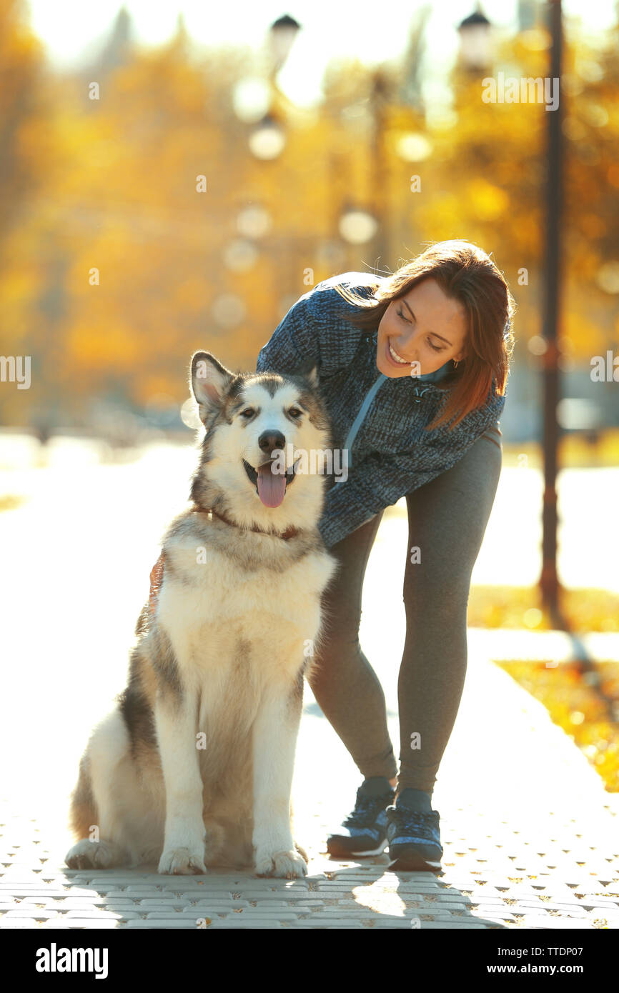 Happy young woman walking with her dog in park Stock Photo - Alamy