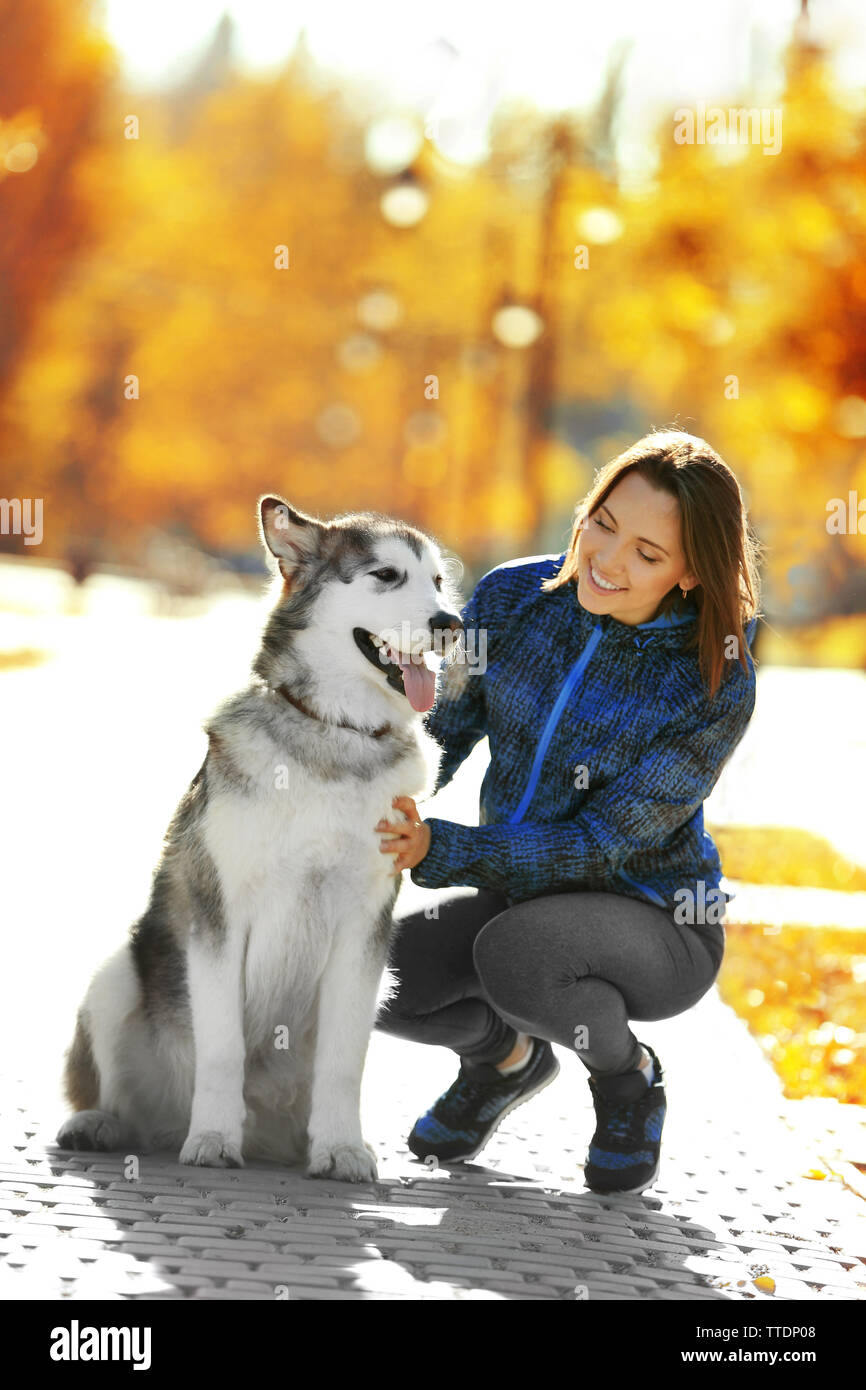 Happy young woman walking with her dog in park Stock Photo - Alamy
