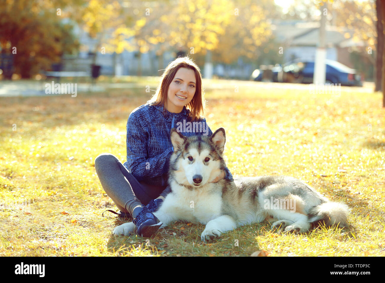 Happy young woman sitting with her dog on grass in park Stock Photo - Alamy