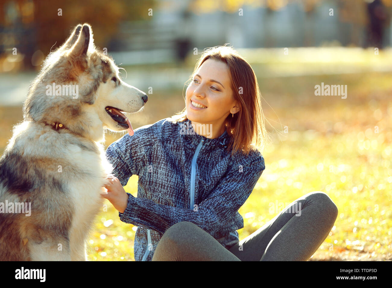 Happy young woman sitting with her dog on grass in park Stock Photo - Alamy