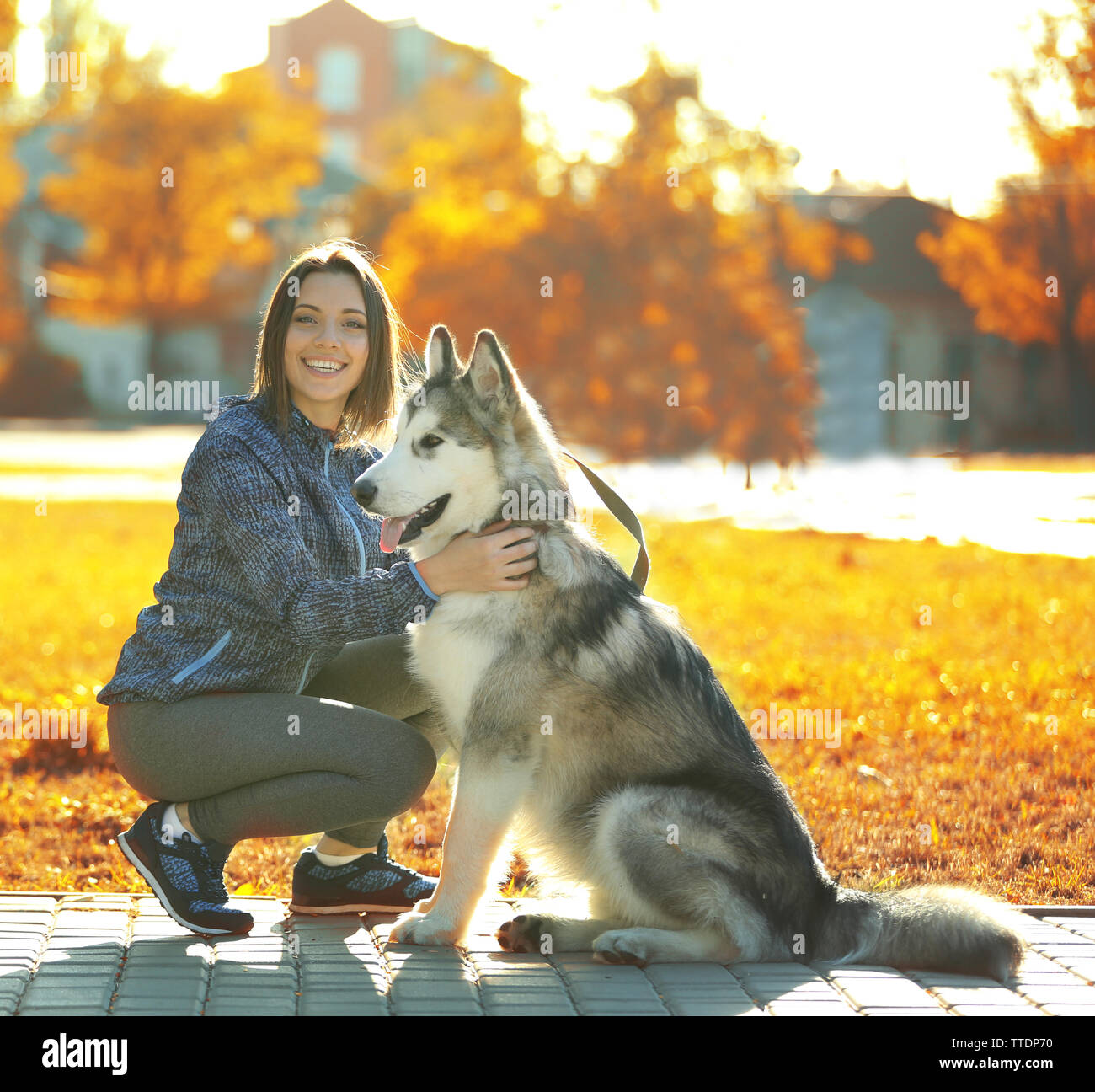 Happy young woman walking with her dog in park Stock Photo - Alamy