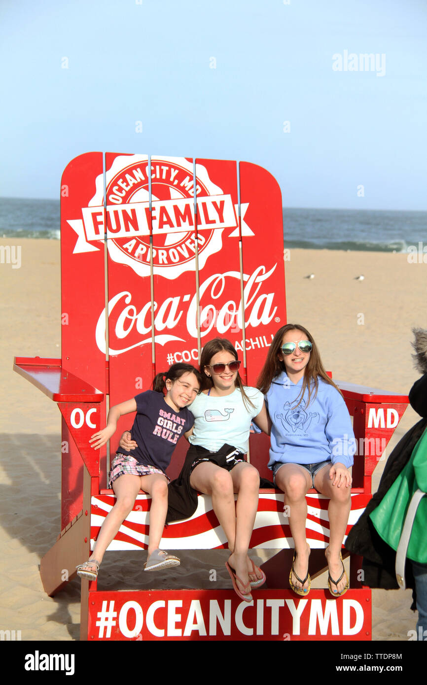 People taking a photo on an oversized Coca Cola chair on the beach of Ocean City, MD, USA Stock Photo