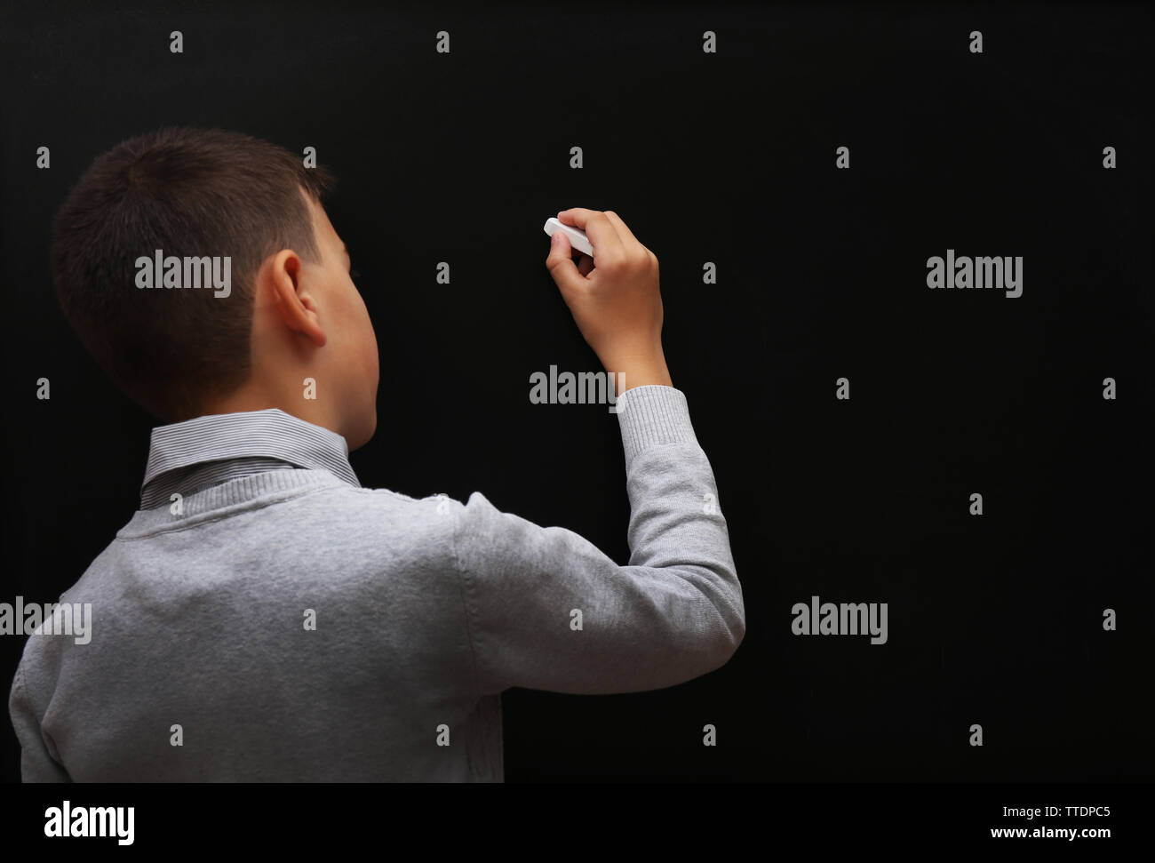 Back view of young schoolboy writing at the blackboard Stock Photo - Alamy