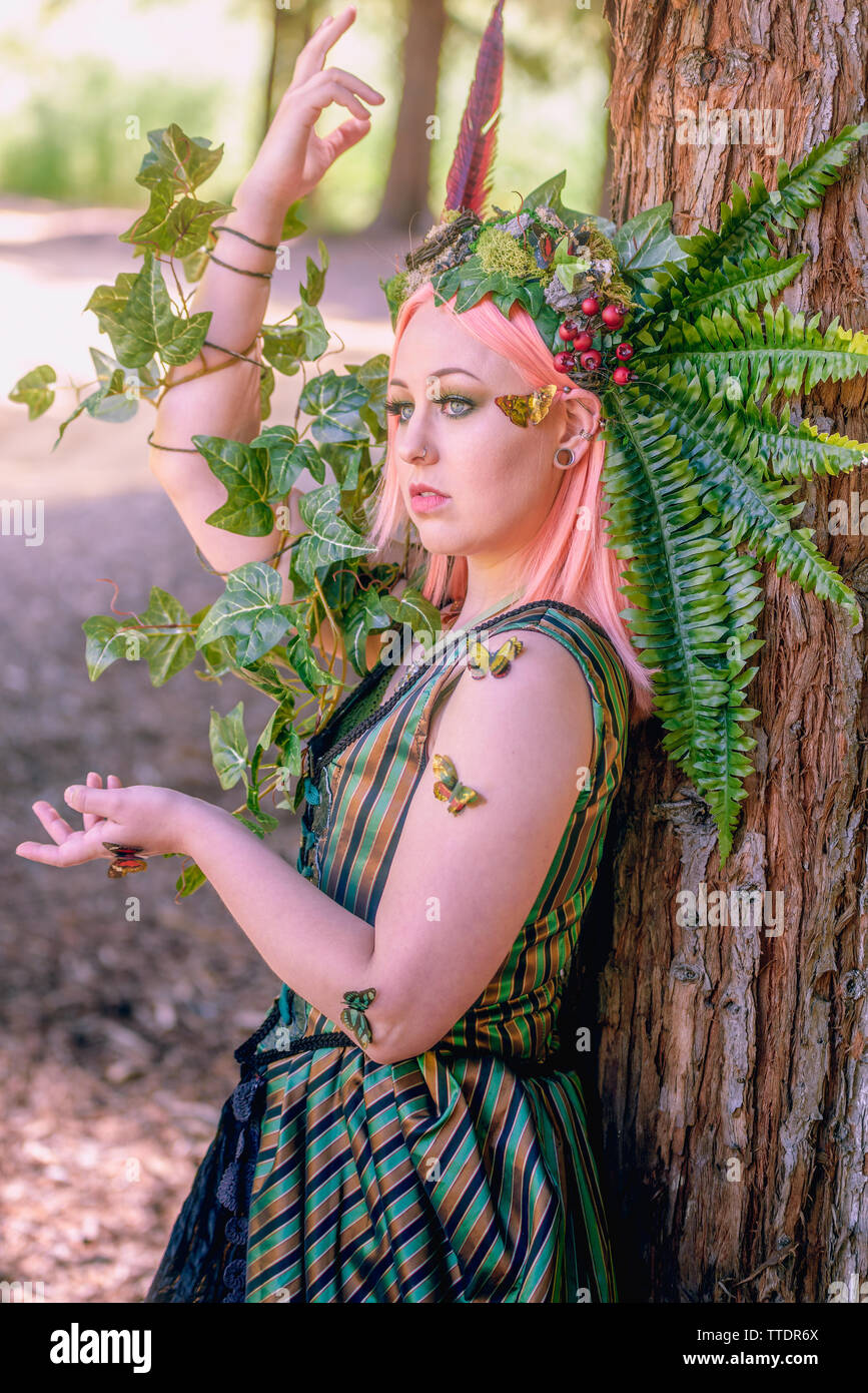 portrait of a caucasian female model with floral headpiece. Model has pastel pink hair and piercings Stock Photo