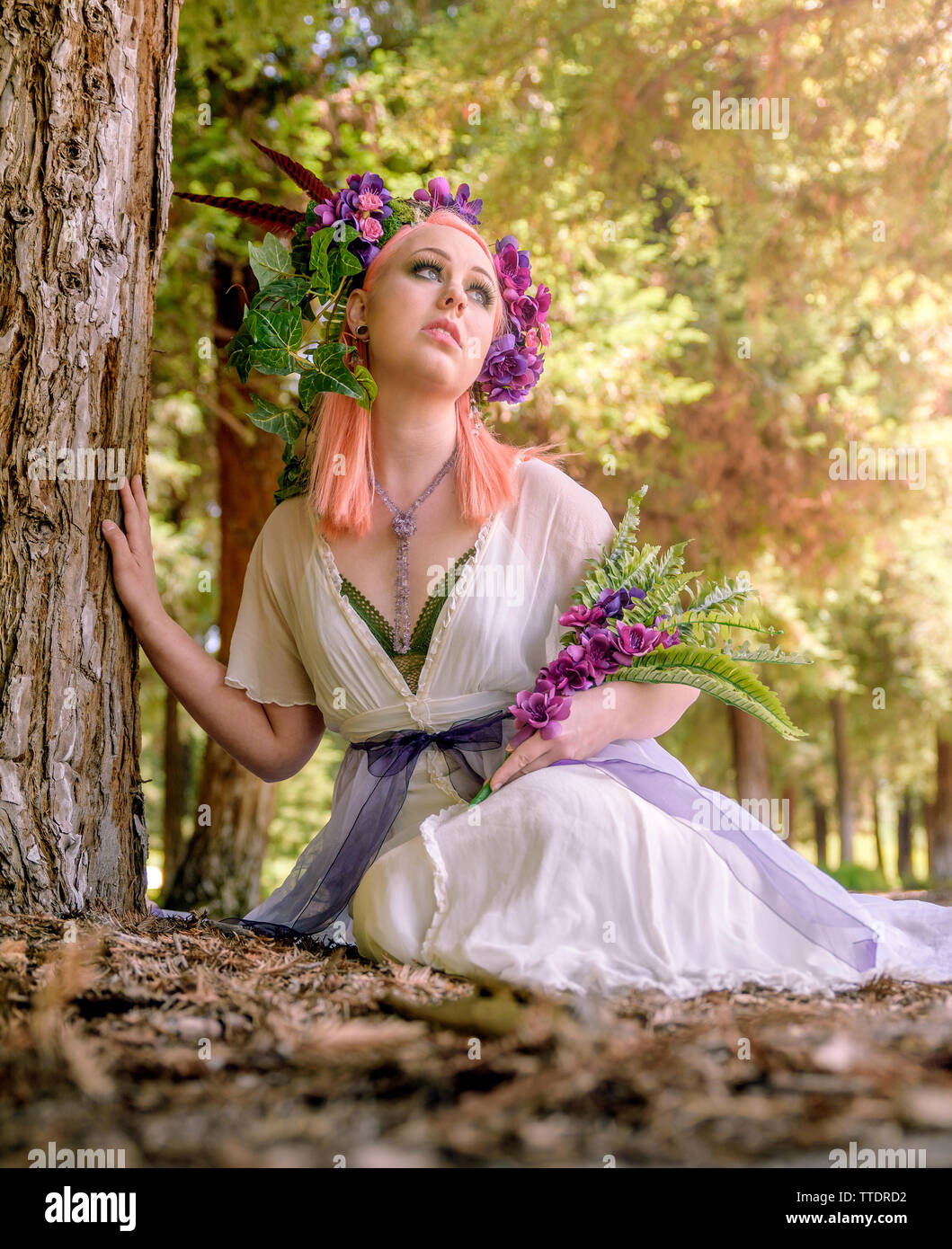 portrait of a caucasian female model with floral headpiece. Model has pastel pink hair and piercings Stock Photo