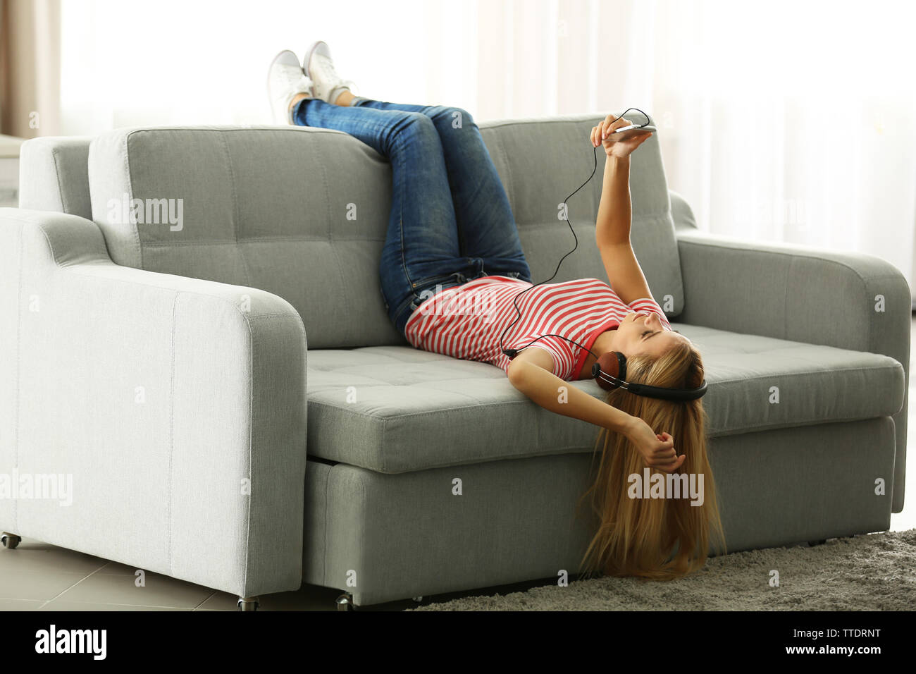 Young woman lying on sofa and listening to music Stock Photo - Alamy
