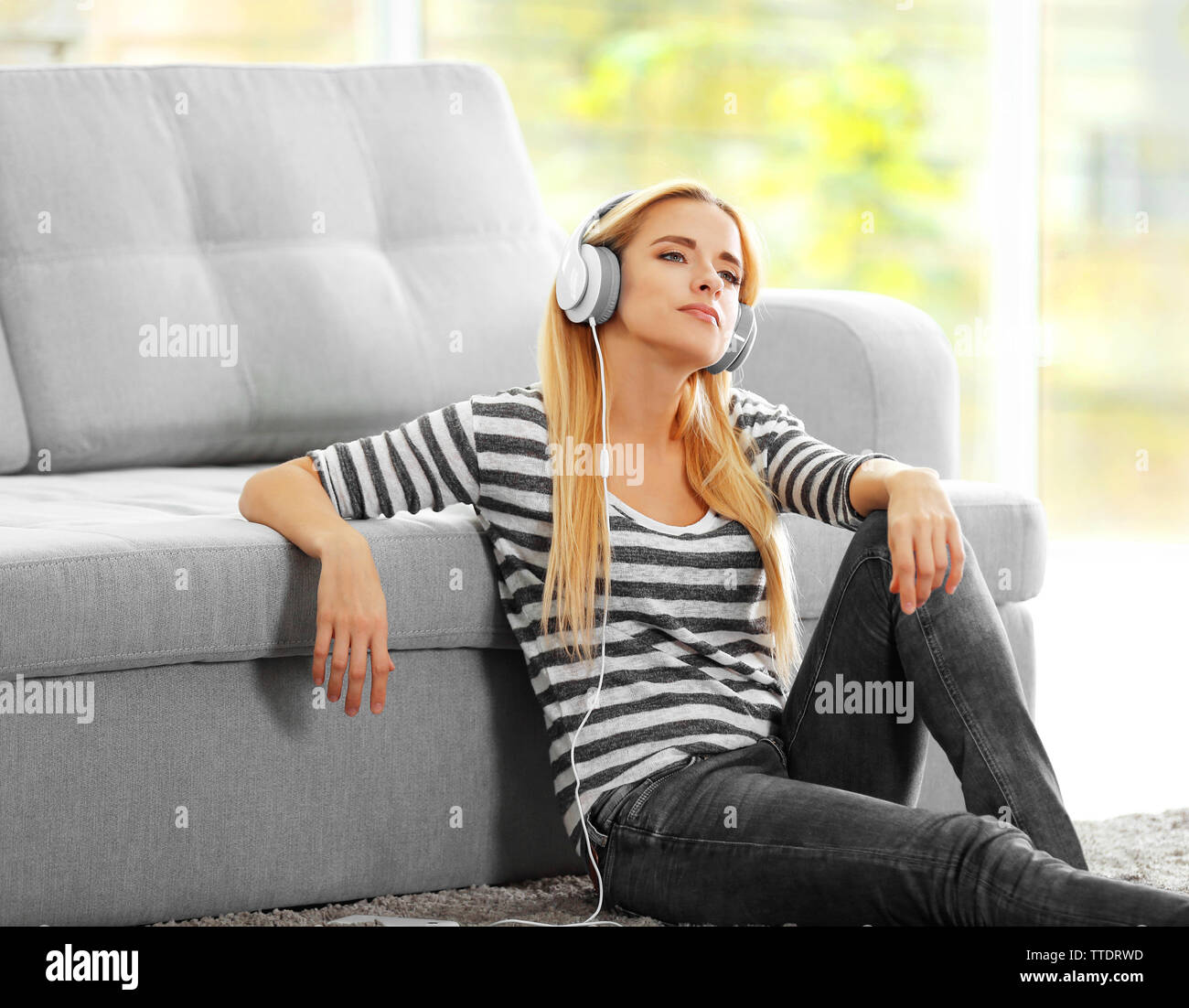 Yong woman sitting on the floor and listening to music Stock Photo - Alamy