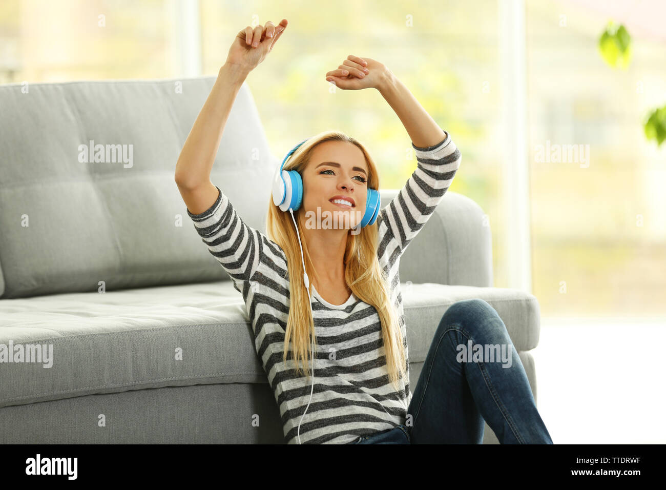 Yong woman sitting on the floor and listening to music Stock Photo - Alamy