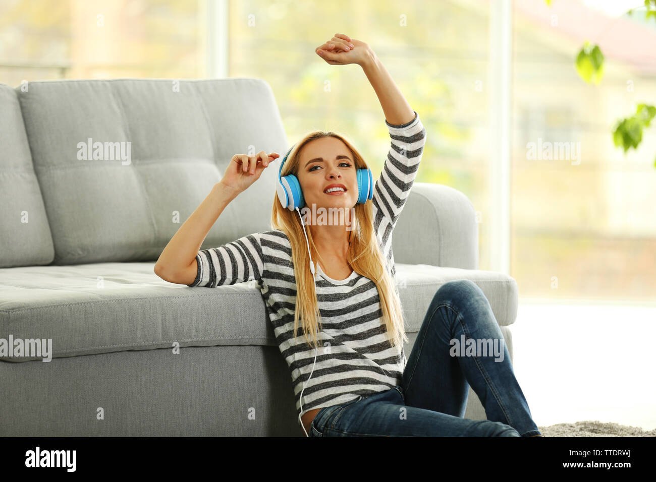Yong woman sitting on the floor and listening to music Stock Photo - Alamy