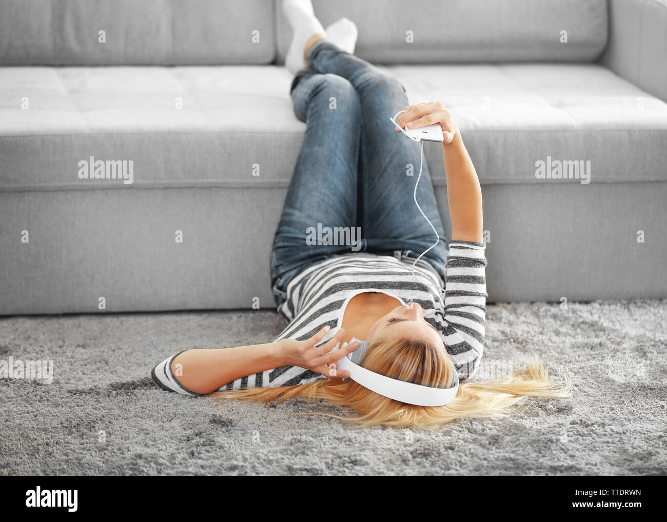 Young woman lying on the floor and listening to music Stock Photo - Alamy