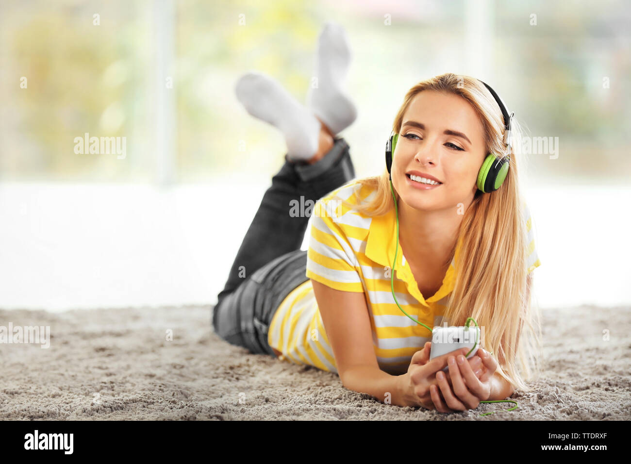 Young woman on the floor in a room listening to music Stock Photo - Alamy