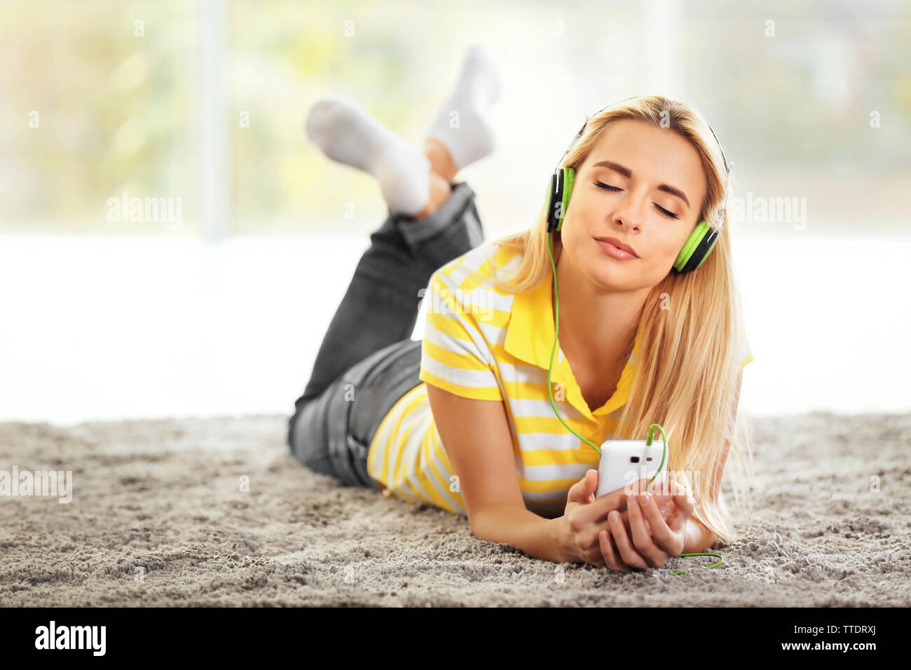 Young woman on the floor in a room listening to music Stock Photo - Alamy