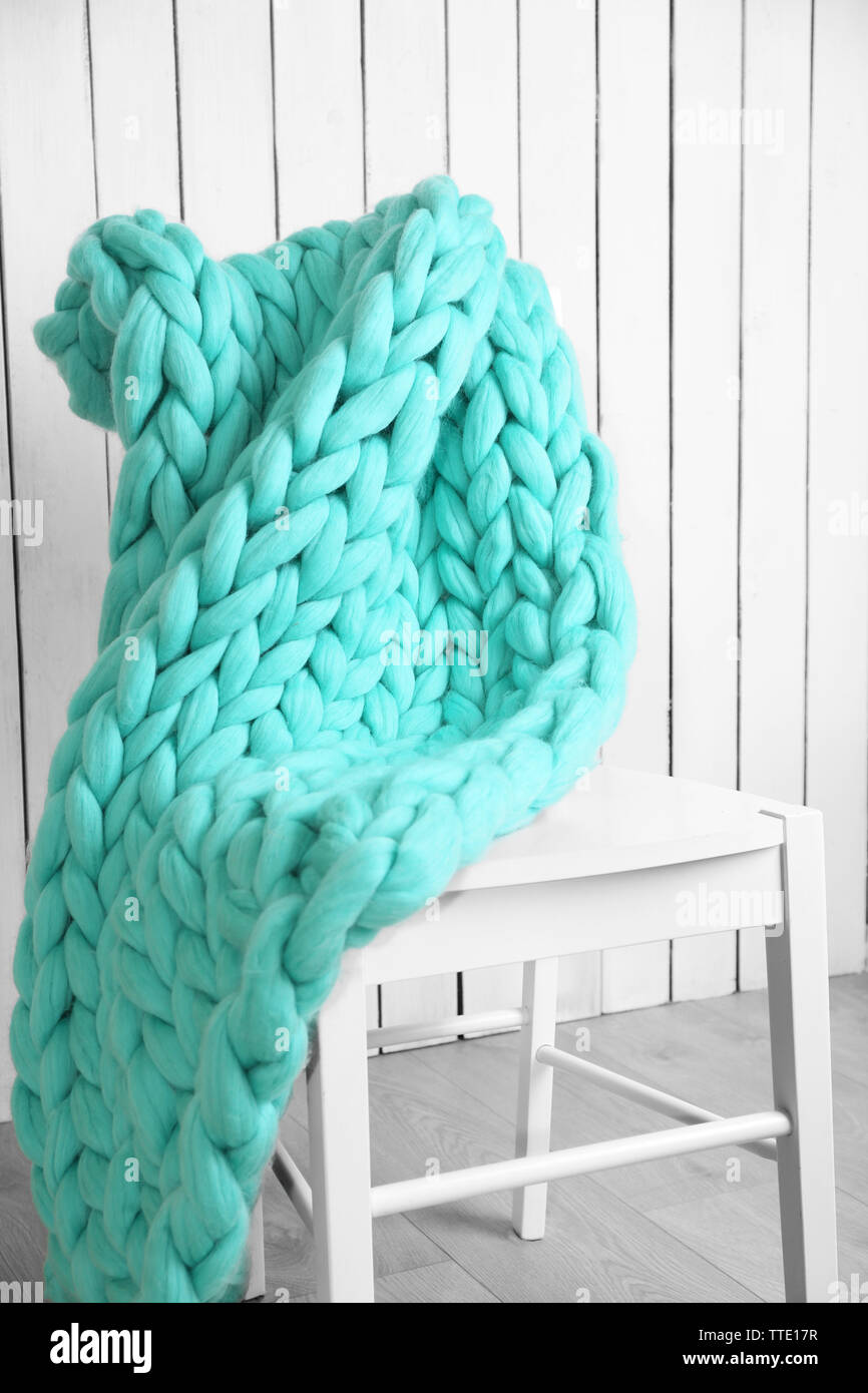 Knitted woolen blanket on chair, on home interior background Stock
