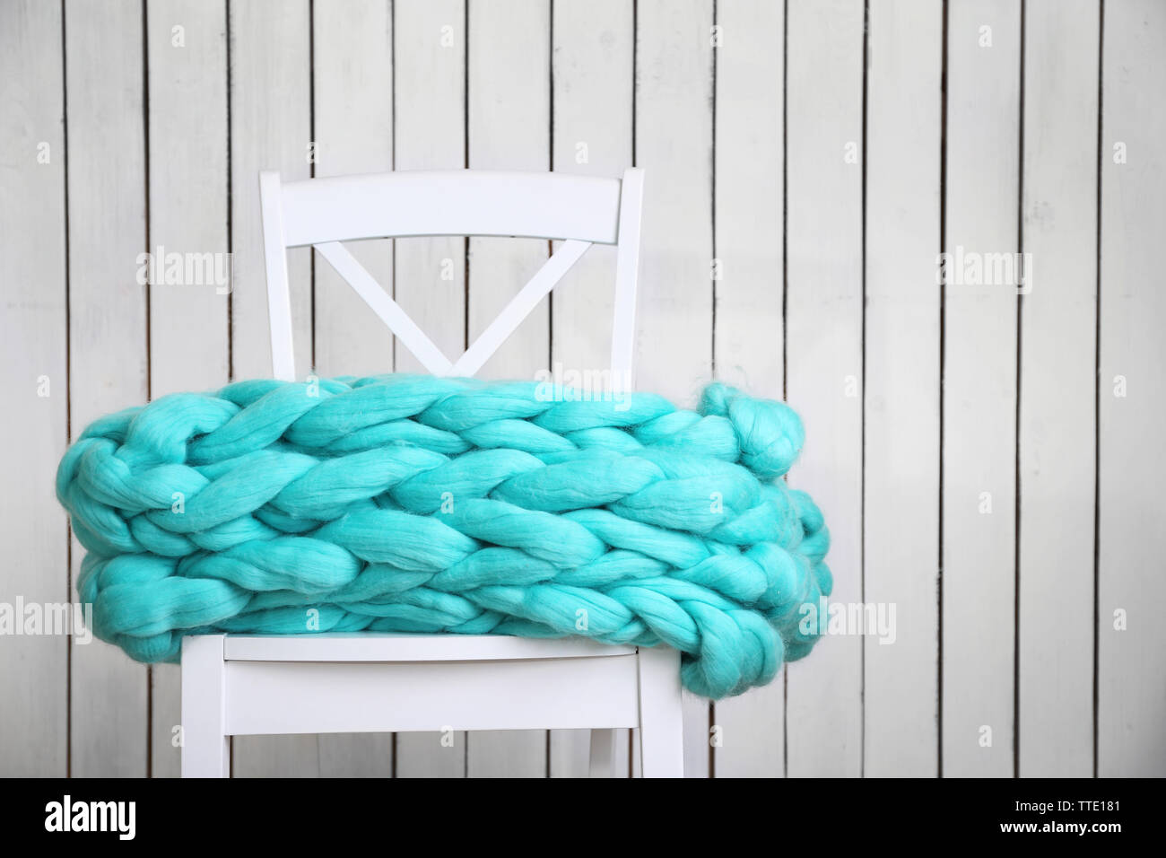 Knitted woolen blanket on chair, on home interior background Stock
