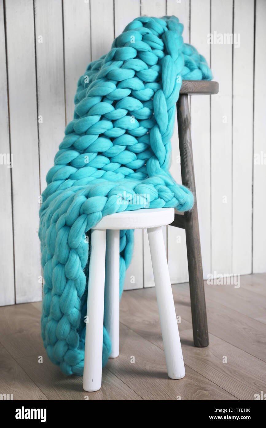 Knitted woolen blanket on chair, on home interior background Stock