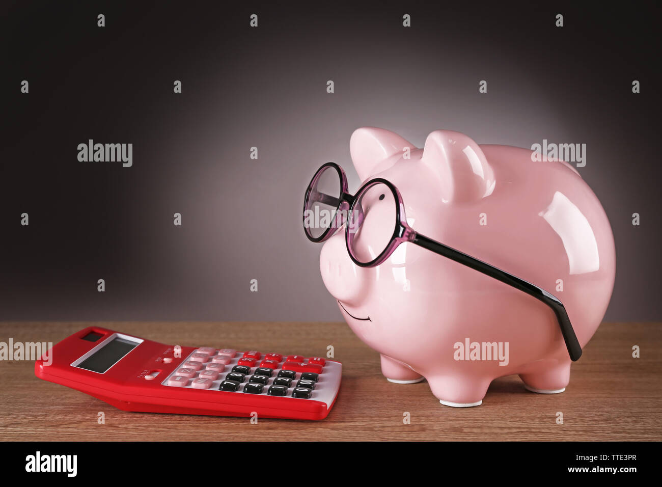 Piggy bank in glasses with calculator on grey background Stock Photo ...