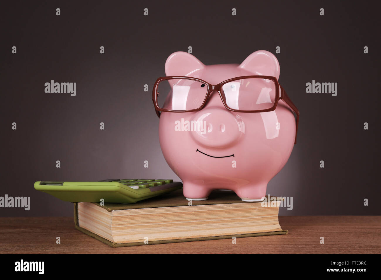 Piggy bank in glasses with calculator and book on grey background Stock ...