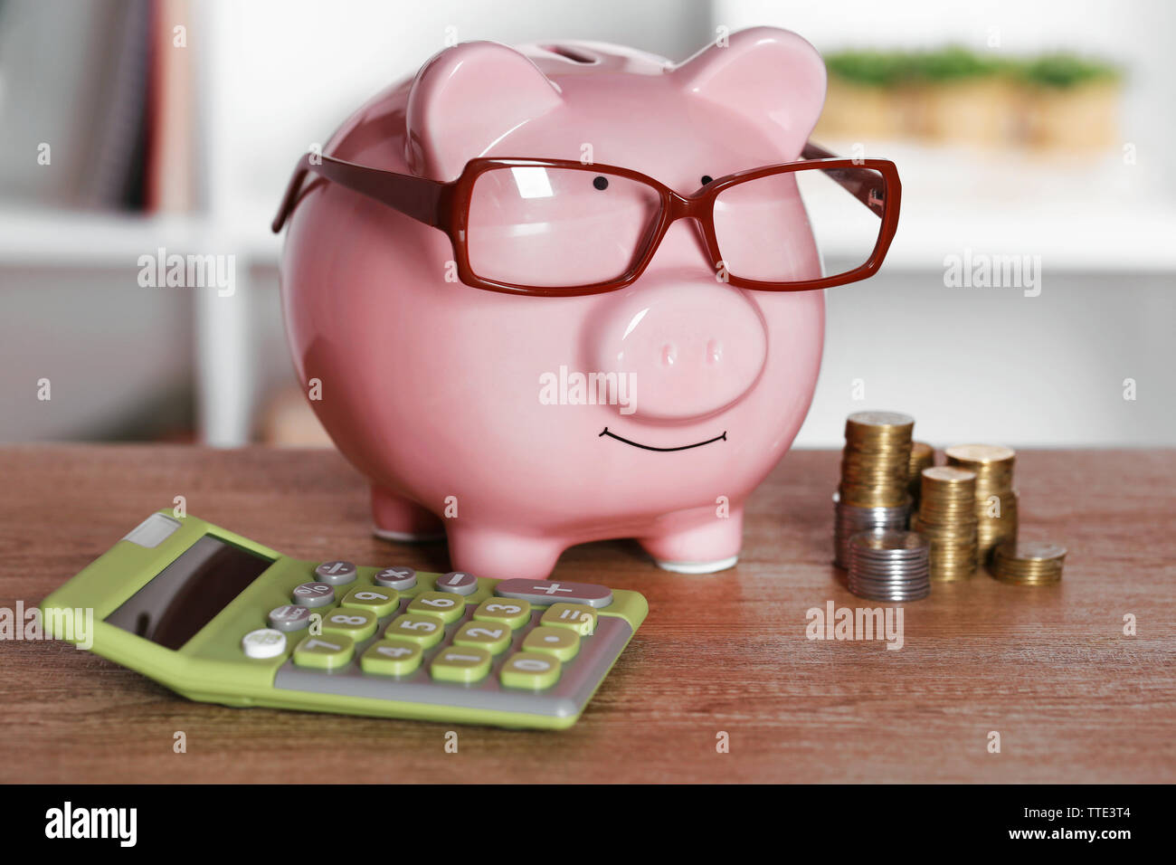 Piggy bank in glasses with calculator and coins on home or office ...