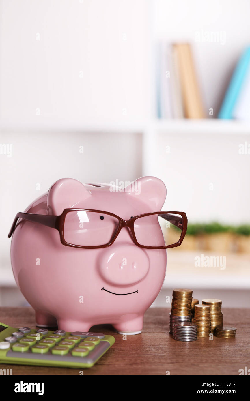 Piggy bank in glasses with calculator and coins on home or office ...