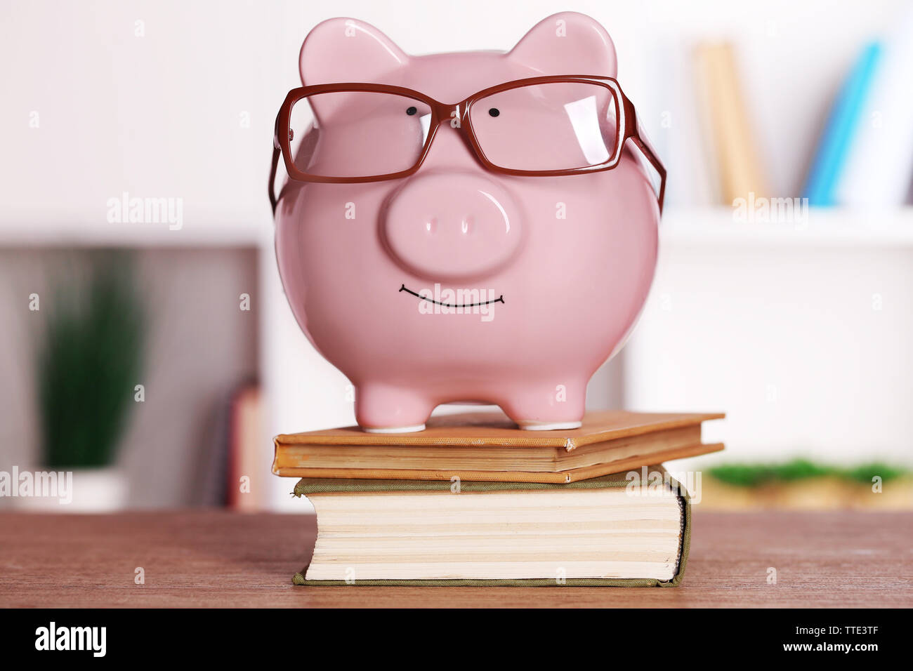 Piggy bank in glasses with books on home or office background Stock ...