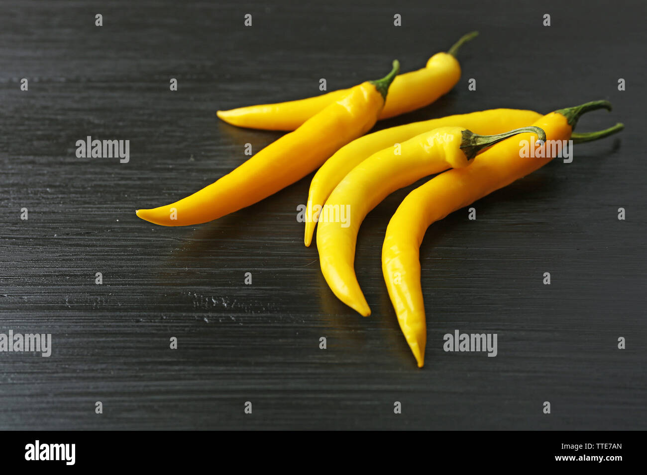 Yellow chili peppers on dark wooden background Stock Photo - Alamy