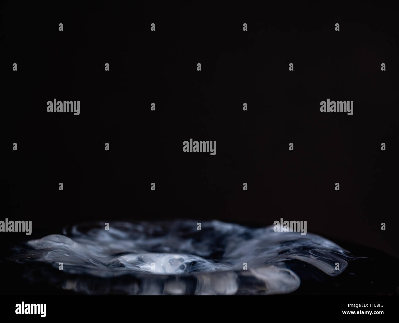 Splash of milk droplets in close up macro high resolution isolated against a black background Stock Photo