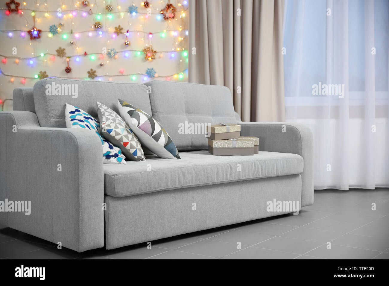 Light Grey Couch With Pillows On Christmas Lights Background Stock