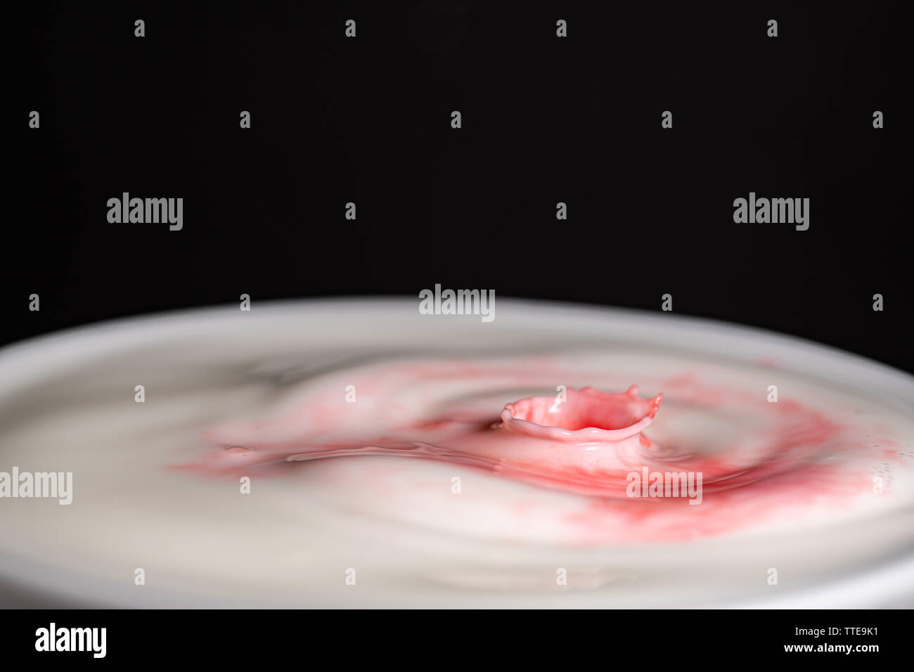 Splash of milk droplets in close up macro high resolution isolated against a black background Stock Photo