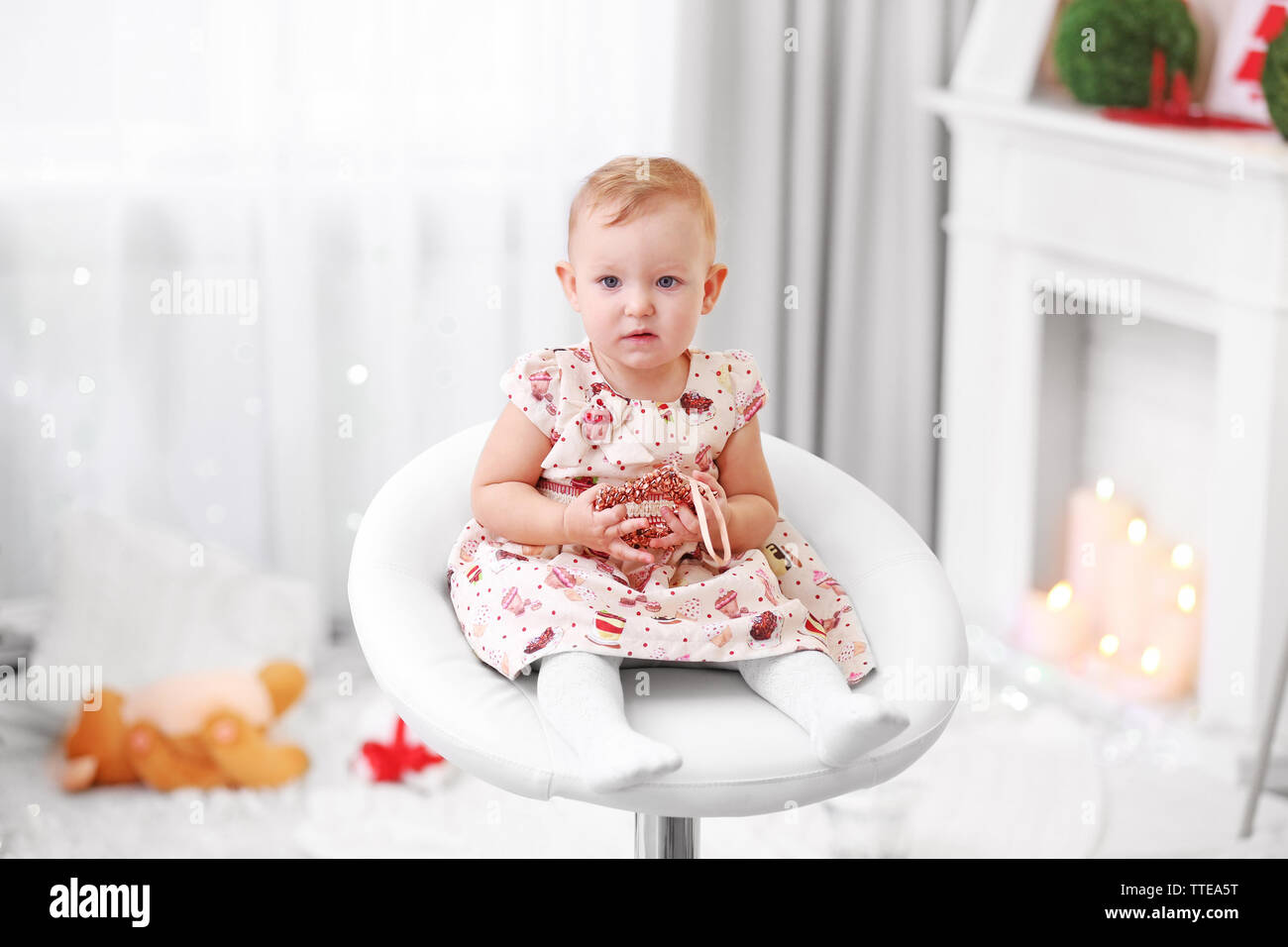 Funny baby girl sitting on chair in Christmas living room Stock Photo