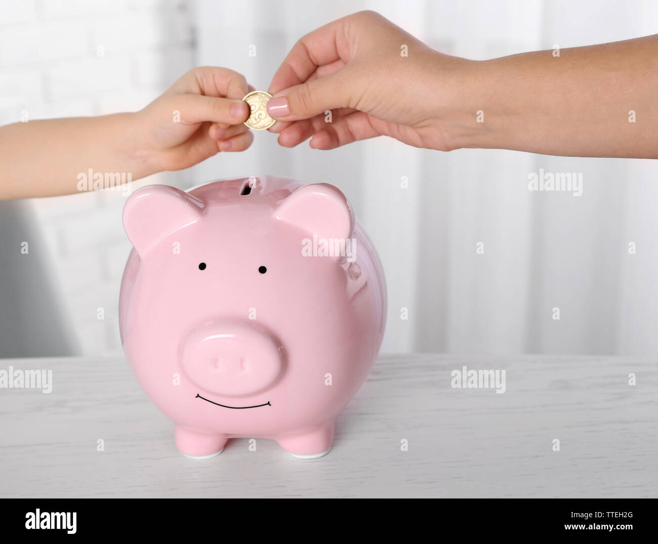 Savings concept. Hand putting coin in the piggy bank, close up Stock ...