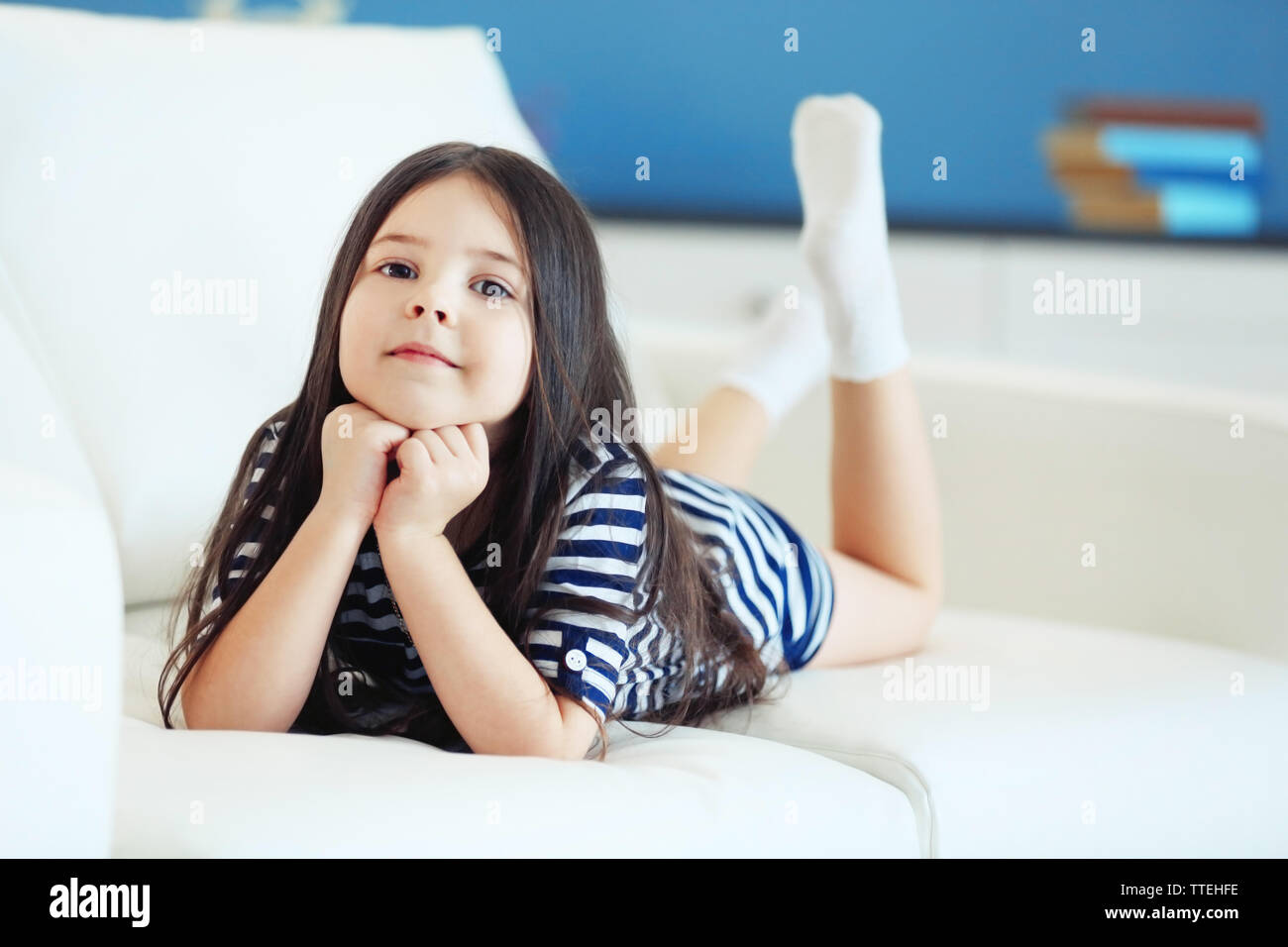 Beautiful little girl lying on sofa in the room Stock Photo - Alamy