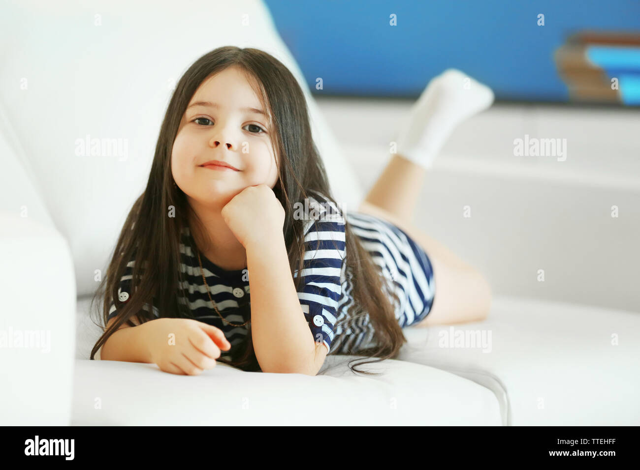 Beautiful little girl lying on sofa in the room Stock Photo - Alamy