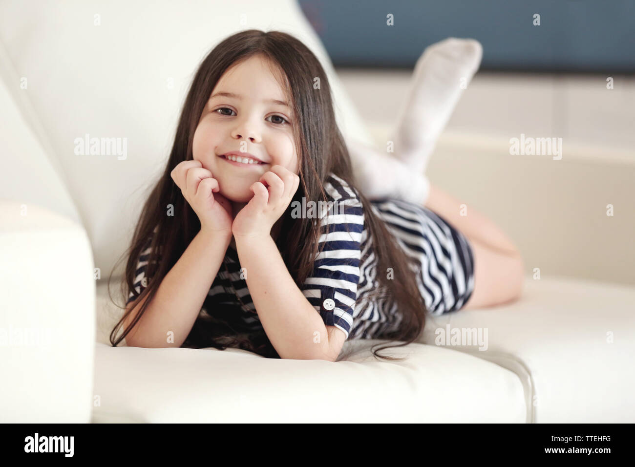Beautiful little girl lying on sofa in the room Stock Photo - Alamy