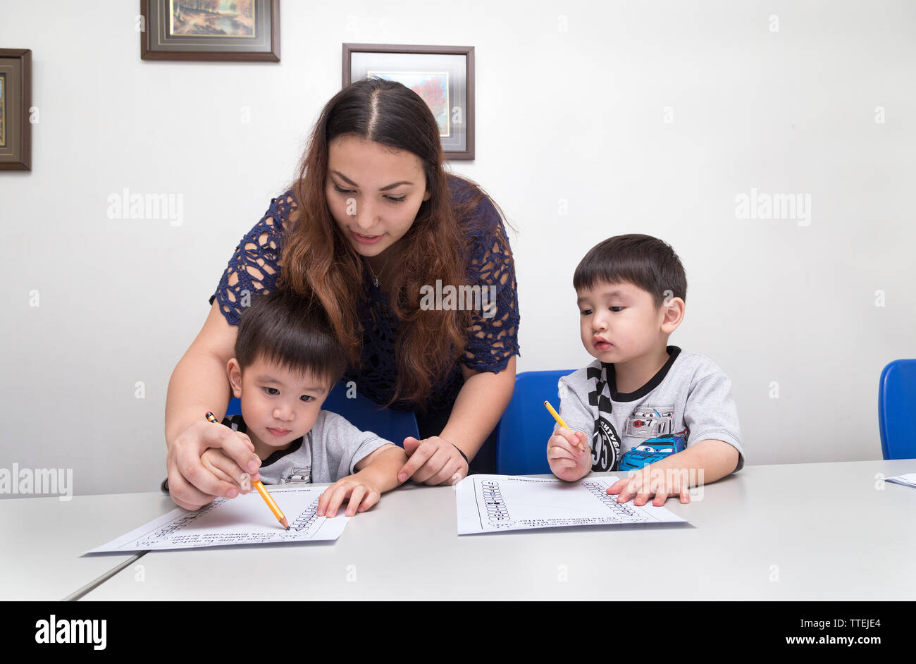 Manila, Philippines - August, 18, 2016: A female teacher teaching two little boys, explaining how to write in classroom at school Stock Photo