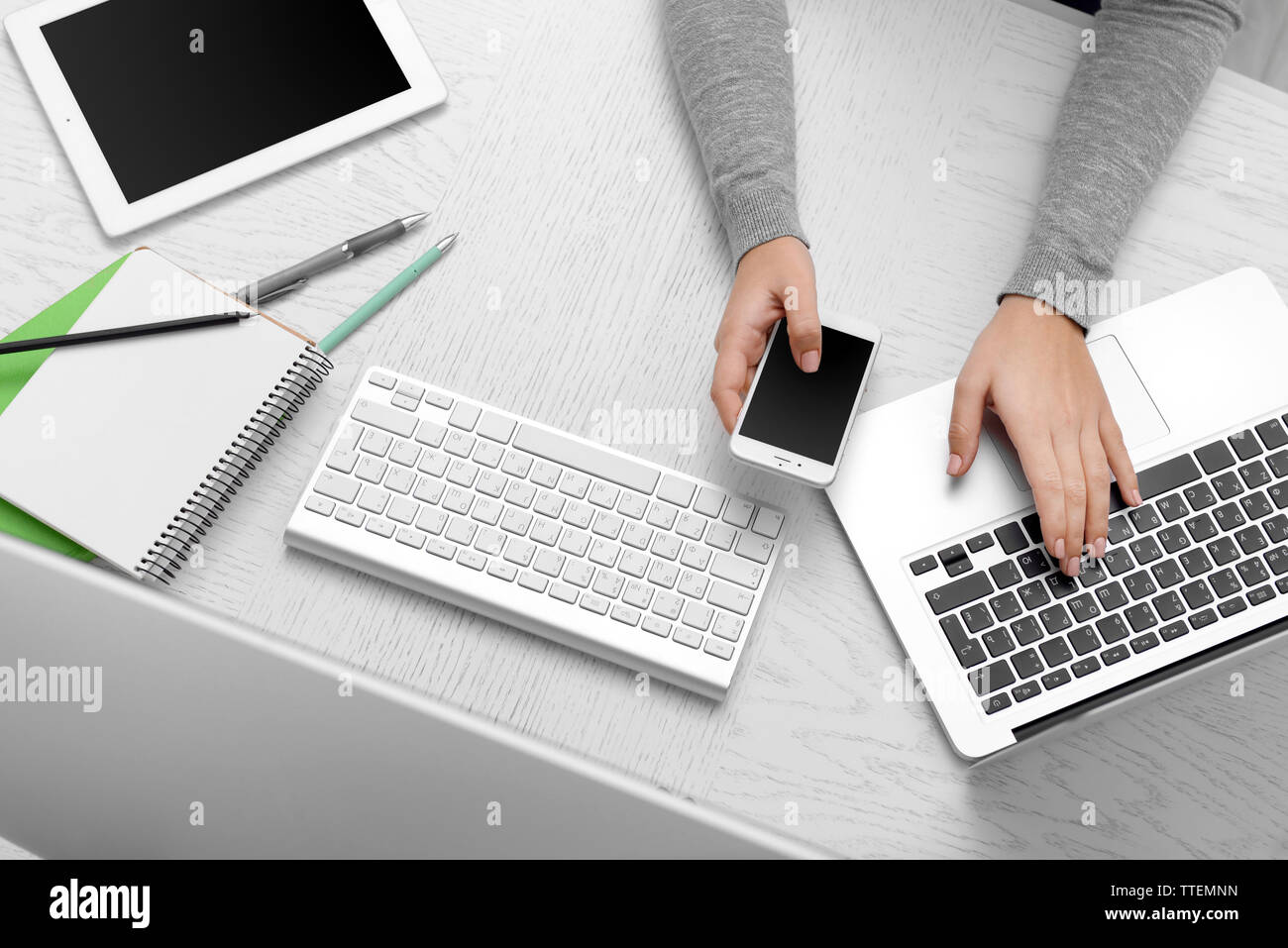 Woman hands at table with computer, tablet, smart phone and other ...