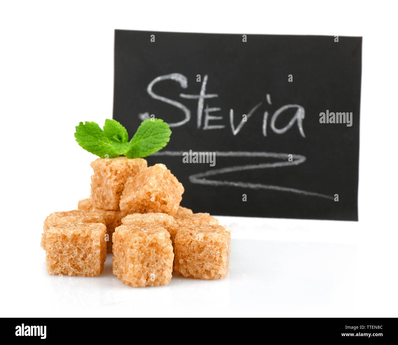 Pile of brown sugar cubes and stevia isolated on white background Stock Photo