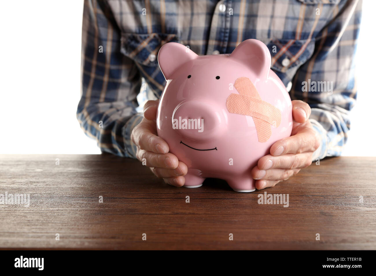 Man holding Piggy Bank with adhesive bandage, on white background Stock ...