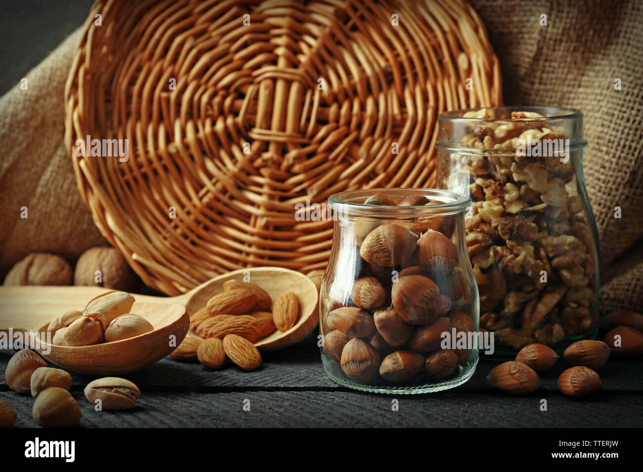 Mix of nuts in the glass jars and wooden spoon, on the table Stock Photo