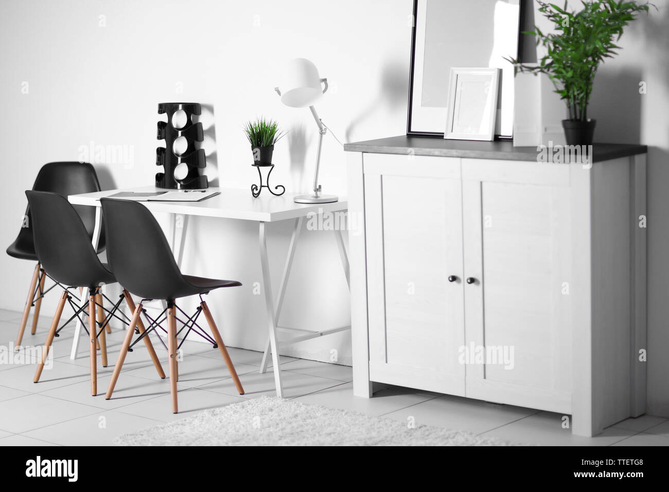 Room interior with commode, frames, chairs and table on white wall ...