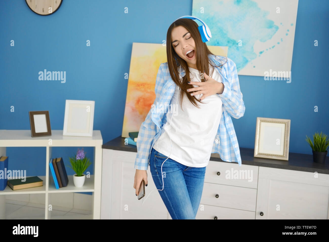 Happy young woman with headphones dancing and listening to music at ...