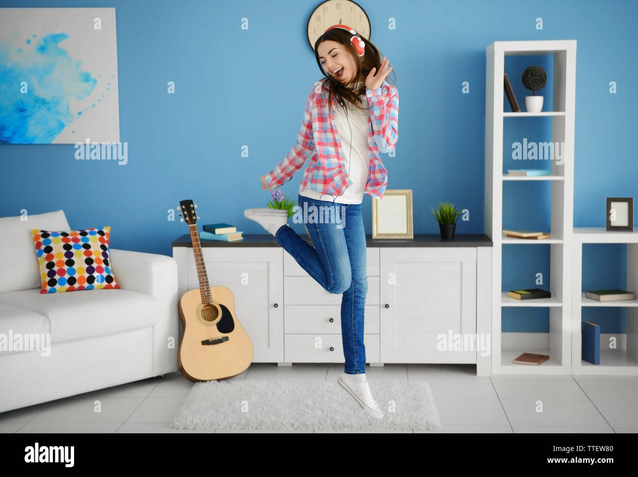 Happy young woman with headphones dancing and listening to music at ...