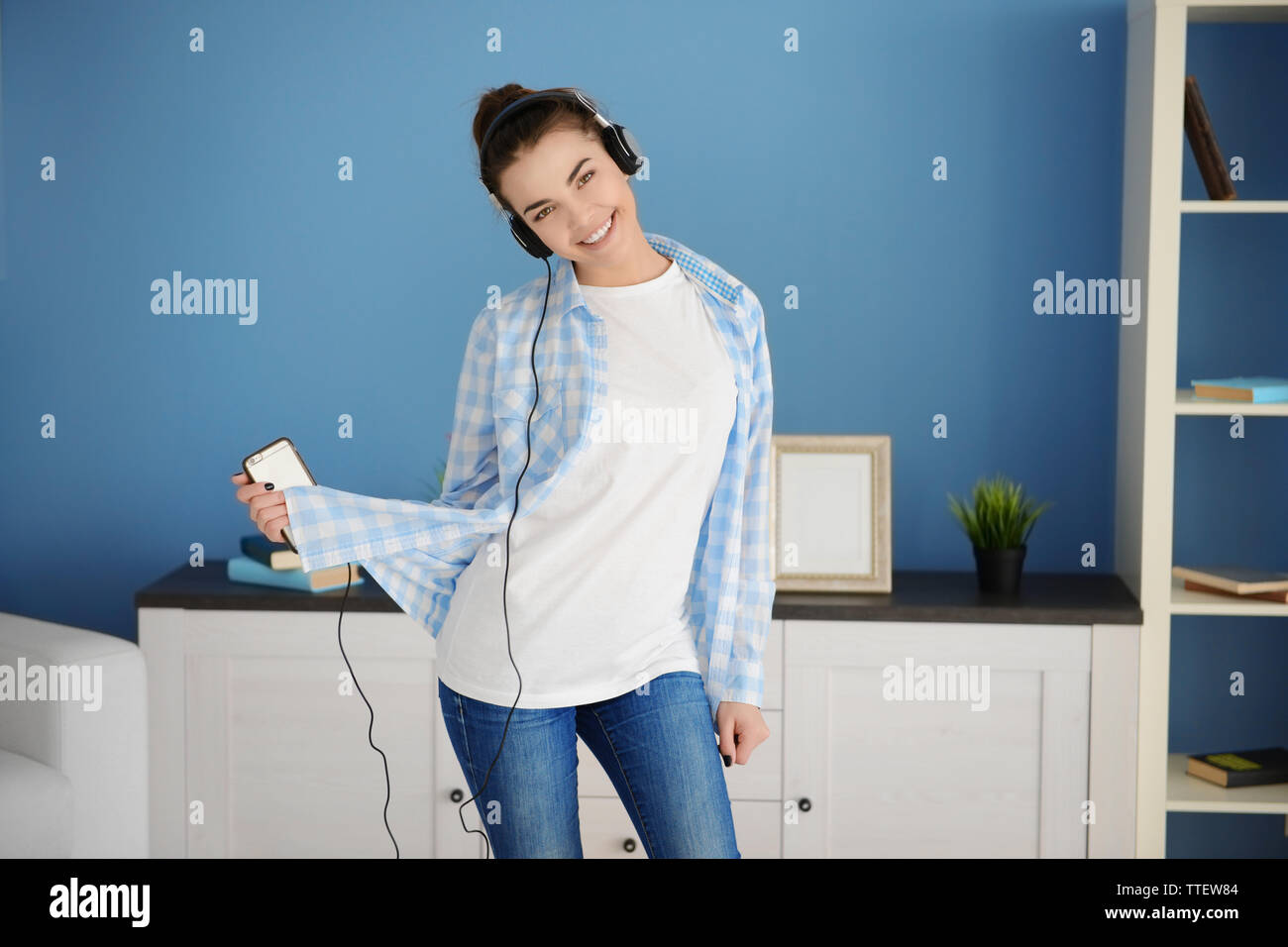 Happy young woman with headphones dancing and listening to music at ...