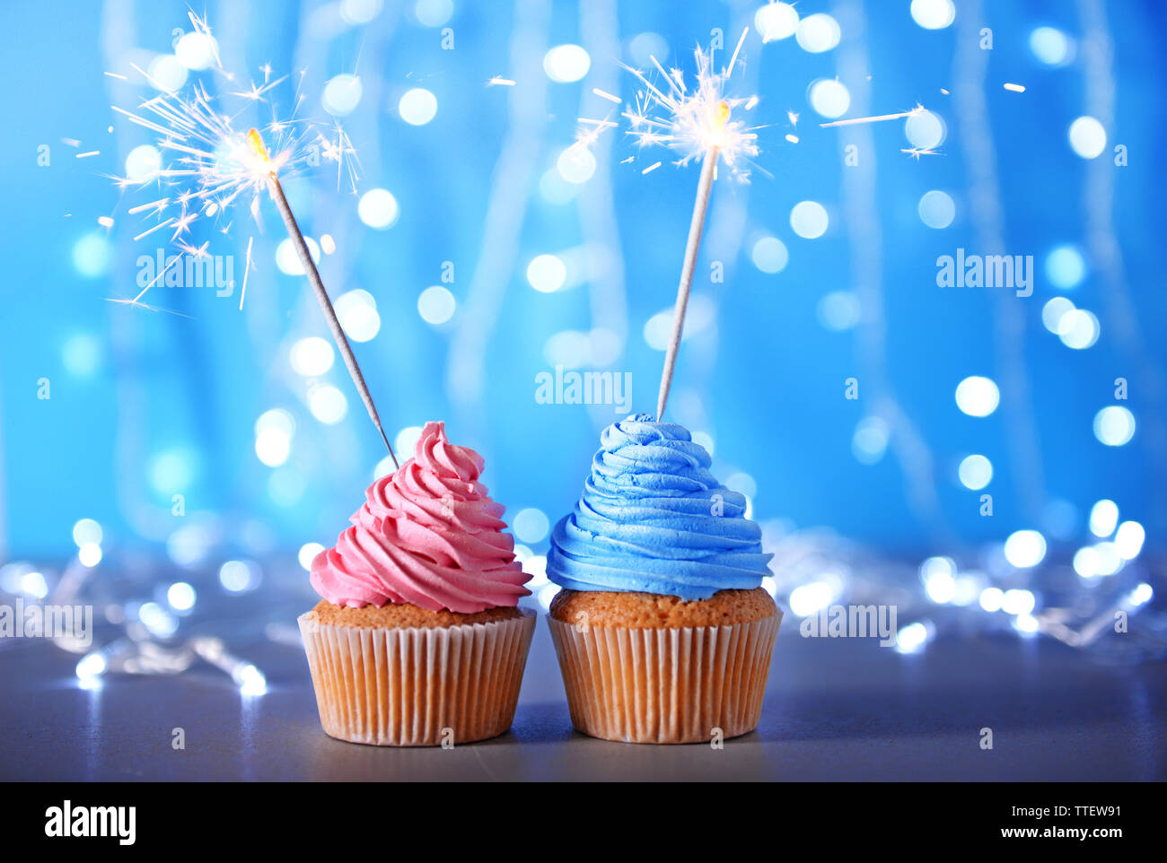 Two cupcakes with sparklers on a glitter background Stock Photo
