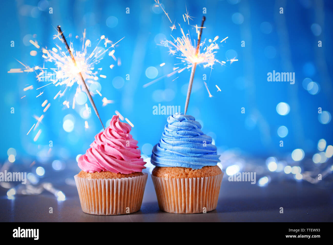 Two cupcakes with sparklers on a glitter background Stock Photo