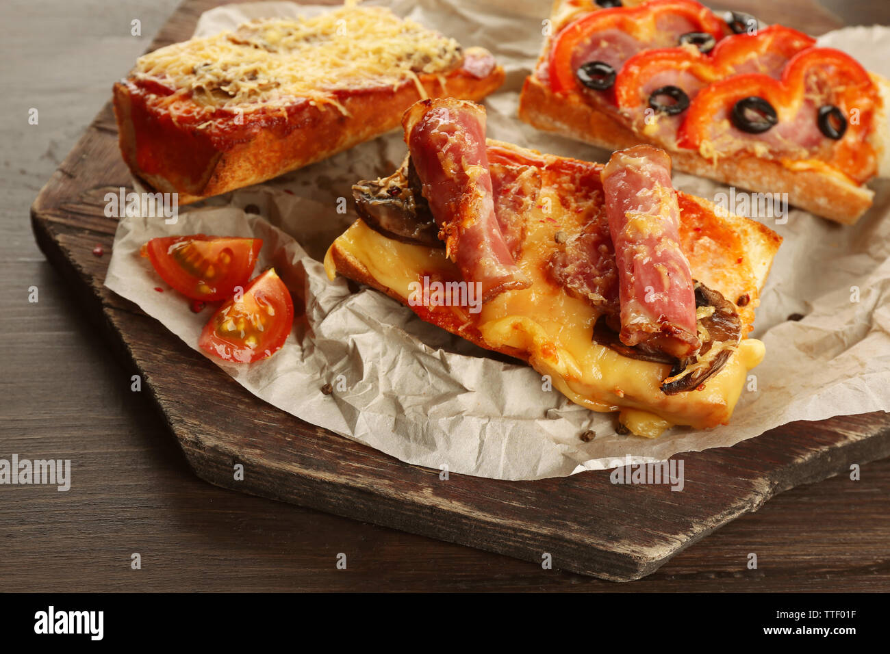 Hot pizza baguettes with bacon, salami and ham on wooden table Stock