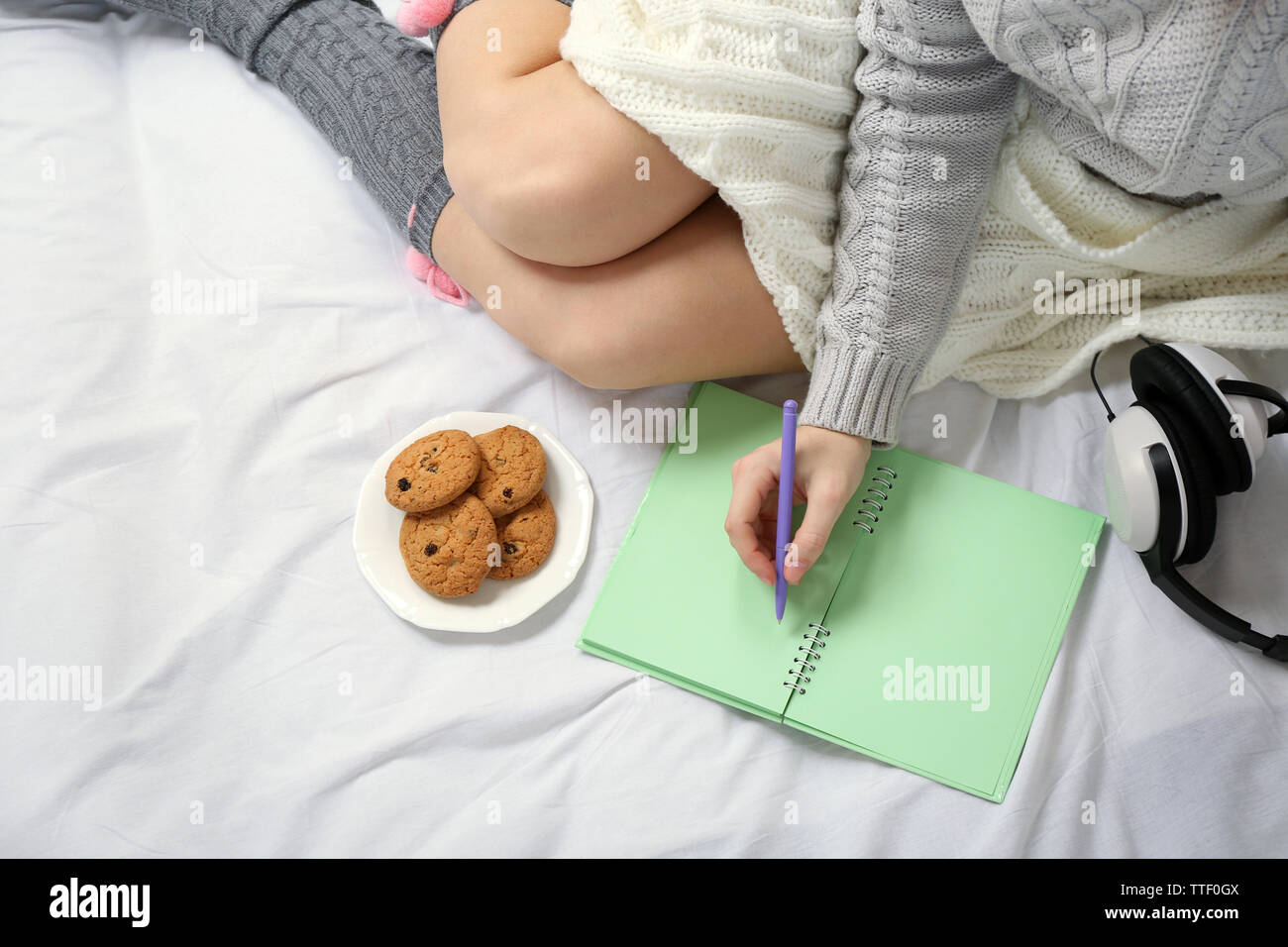Woman with headphones writing diary on her bed Stock Photo