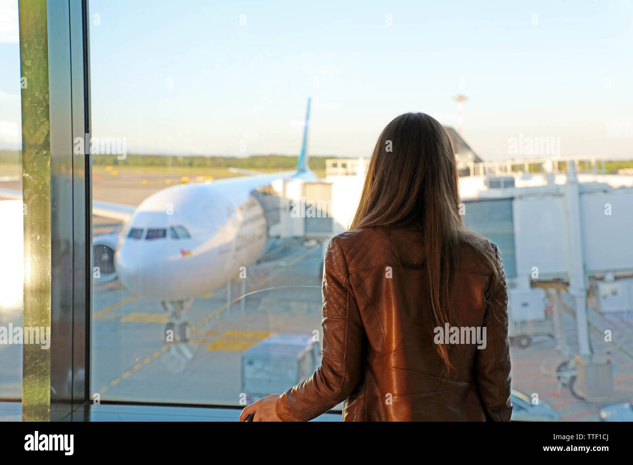 Young woman in the airport looking through the window at airplanes Stock Photo