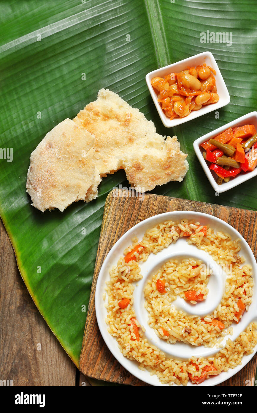 Fried rice with vegetables and flat bread on banana leaf over wooden ...